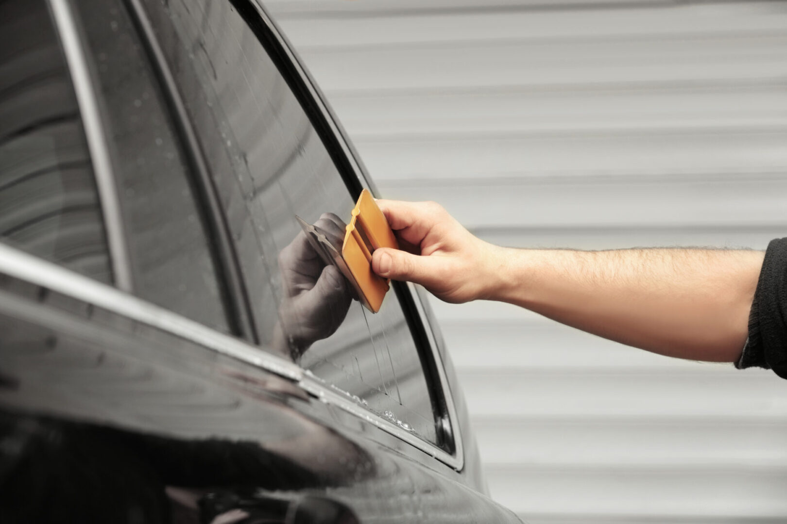 A person is cleaning the side of their car.