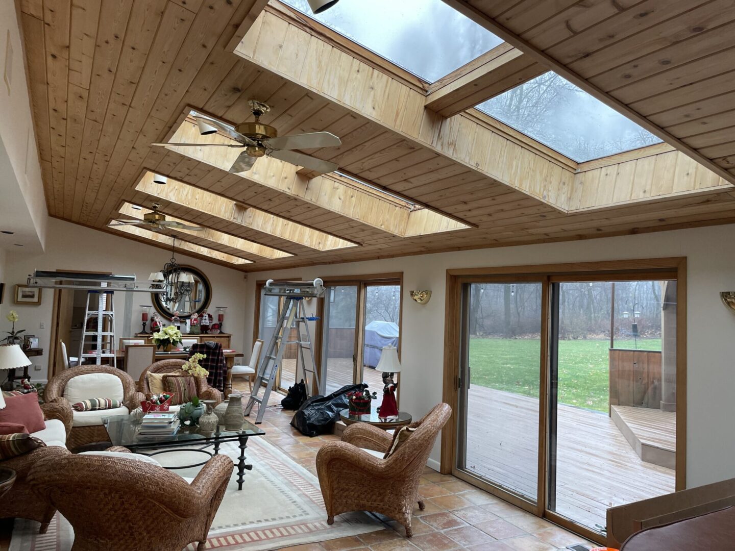 A living room with a large open window and wooden ceiling.