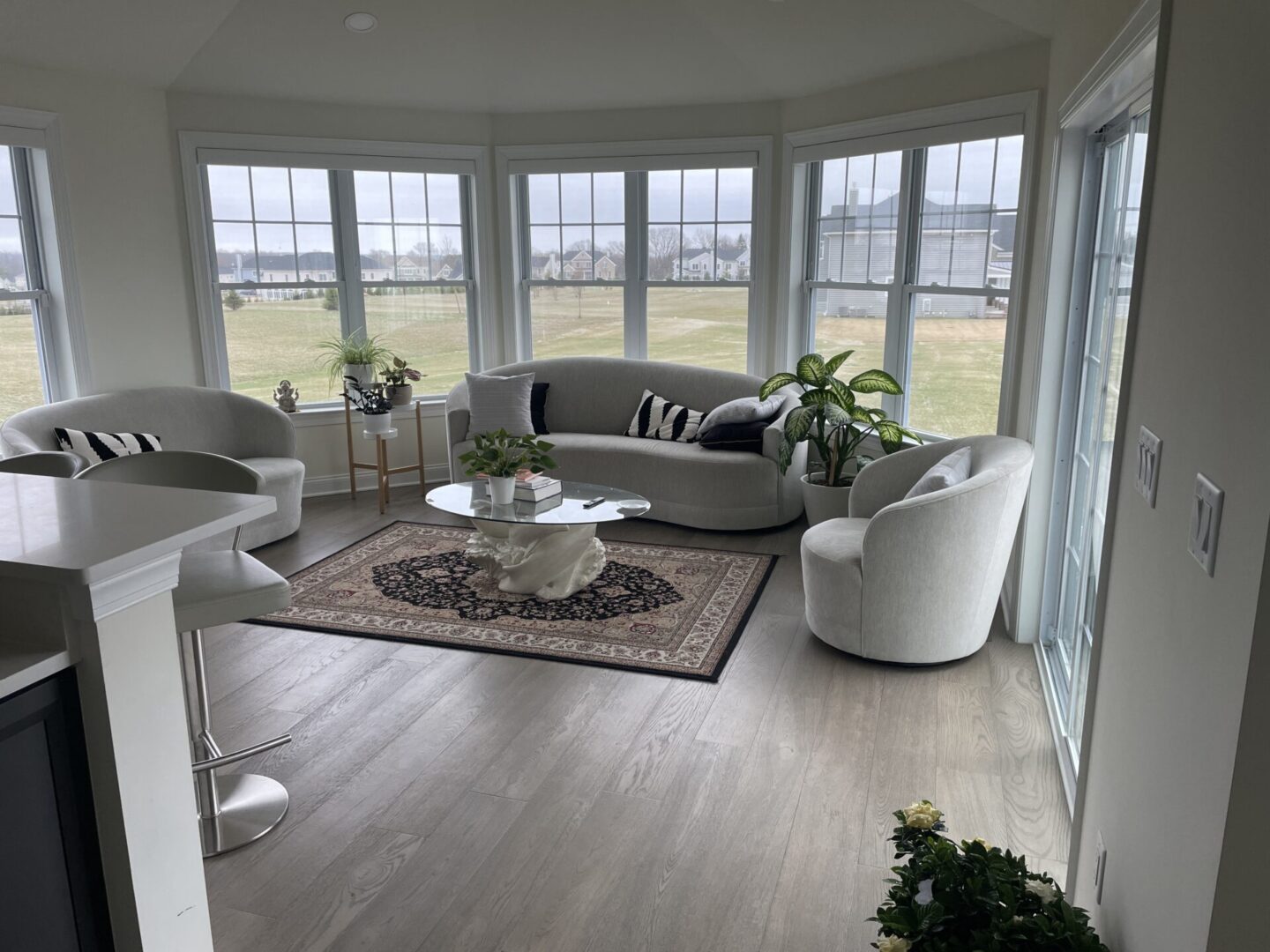 A living room with large windows and white furniture.