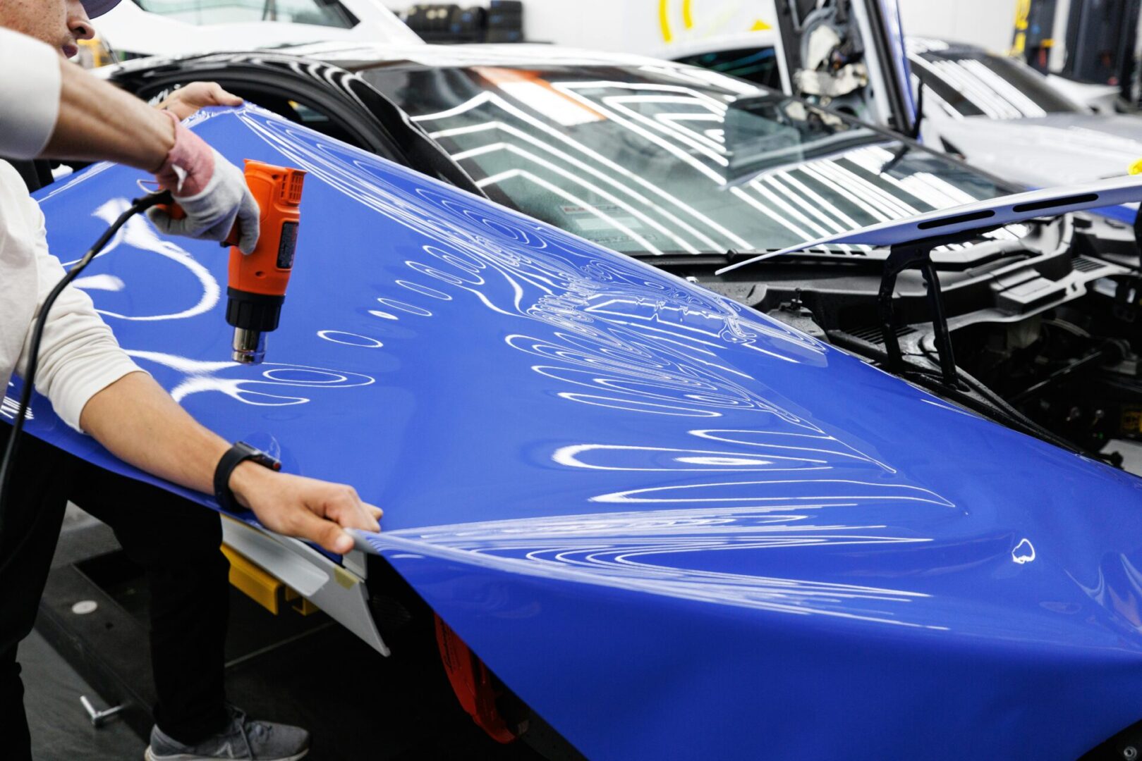 A person is painting the hood of a car.