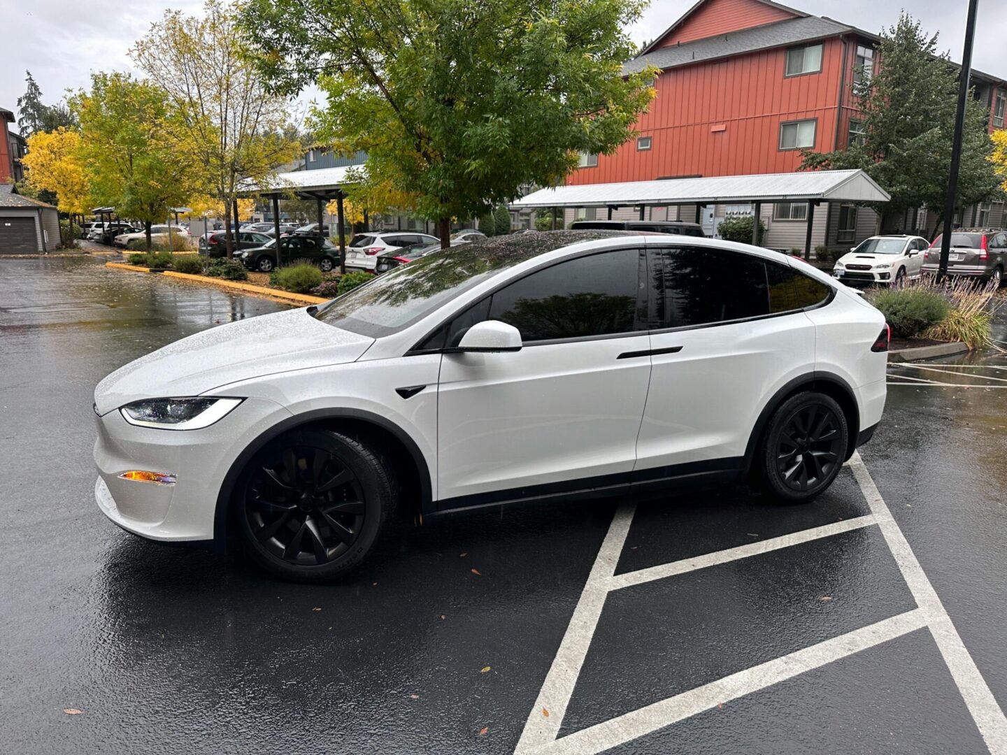 A white car parked in the parking lot of a building.