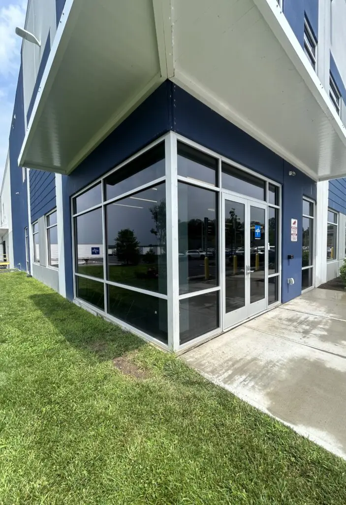 A building with glass windows and grass in front of it.